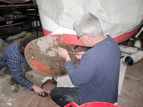 Scrapping paint and rust from the rudder.